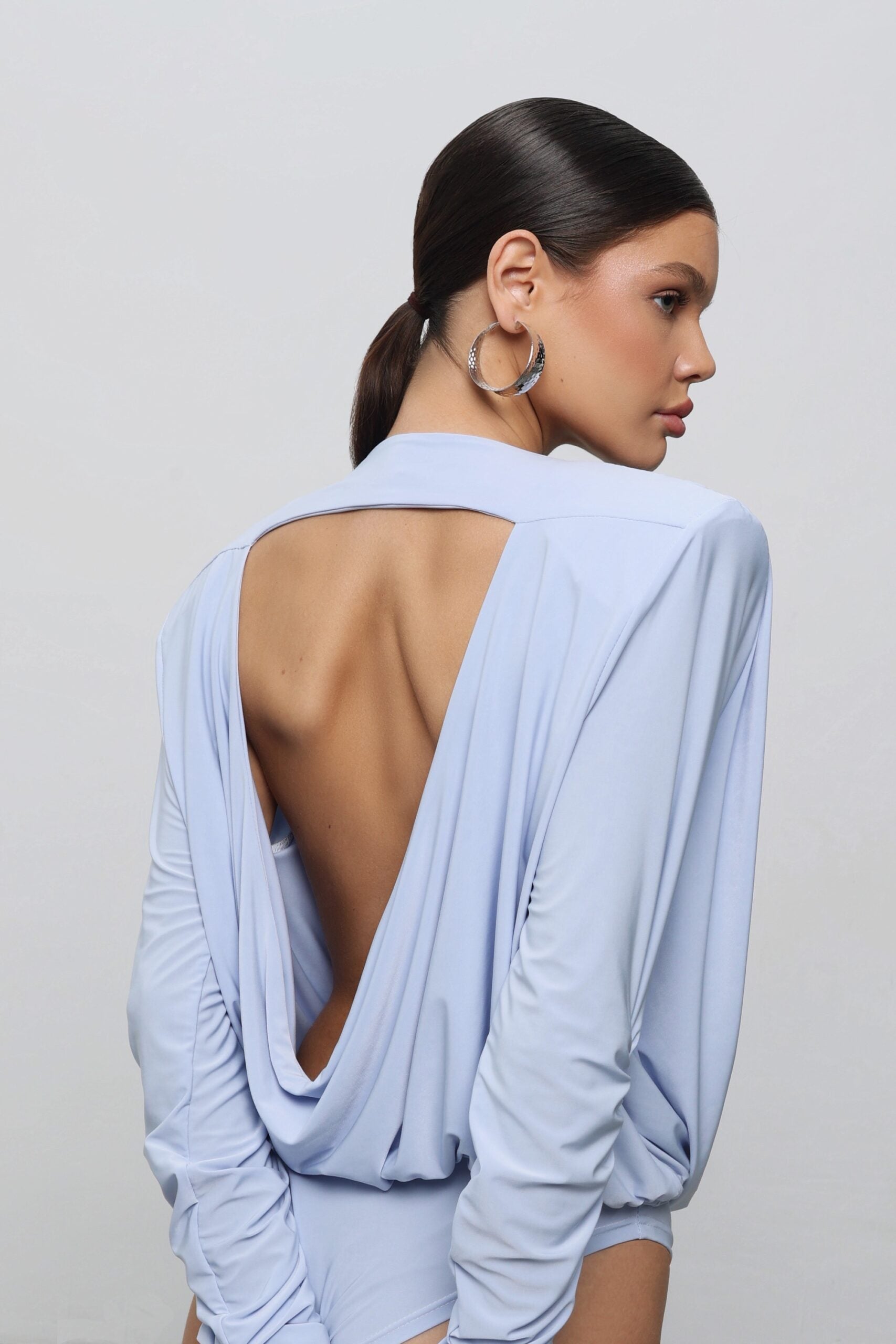 A bodysuit with voluminous shoulders and an open back